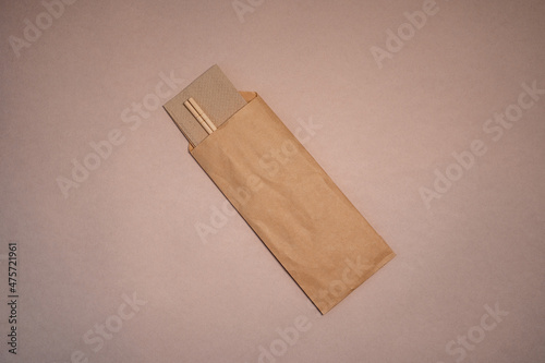 Fototapeta Naklejka Na Ścianę i Meble -  Chinese sticks stick out of craft paper packaging on beige background, isolated