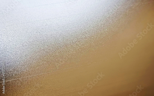 gold brushed metal texture used as background for luxury or glamour concept. close up gold stainless hairline background. steel plate with reflections (focused at center of image).