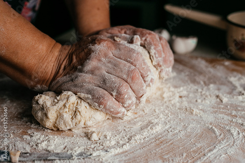 Photos hands close-up kneading dough on a wooden board
