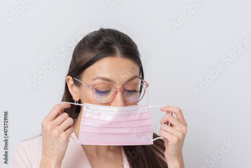 Salisbury, Wiltshire,UK. 2021. Woman wearing glasses placing a pink coloured medical mask on her face during covid.