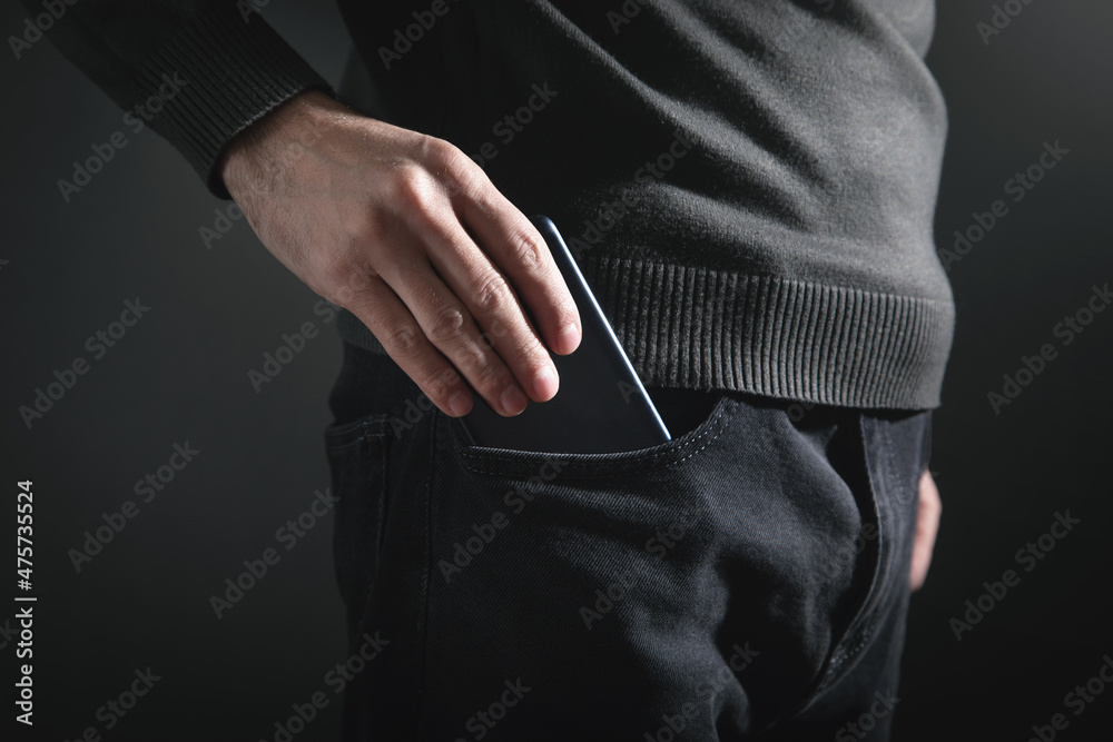 Man putting smartphone in pocket of jeans. Man putting smartphone in pocket of jeans.
