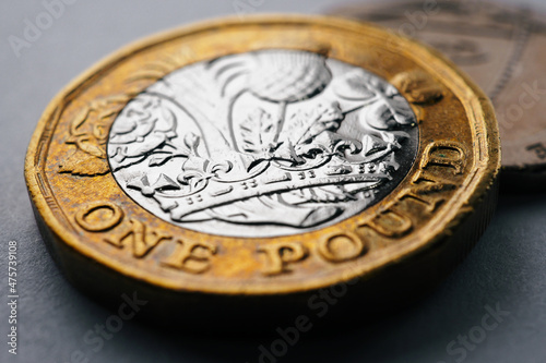 British money lies on a dark surface. 1 pound sterling coin close up. Focus on the crown. Economy and banking in England. Macro