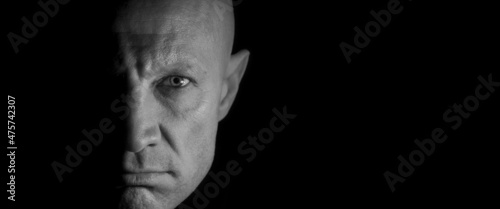 The male face is half lit, black and white photo. Concept: killer in the dark. Night ghost.