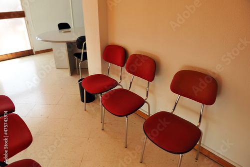 Red upholstered chairs inside a public administration citizen service office. Impersonal interior design vintage decoration  photo