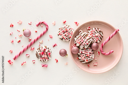 Fototapeta Naklejka Na Ścianę i Meble -  Plate with tasty candy cane cookies and Christmas balls on white background
