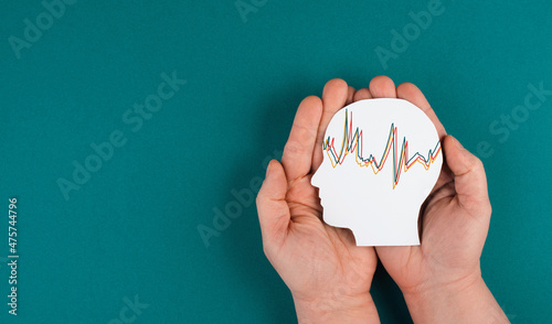 Holding a head in the hands, mental health concept, alzheimer and epilepsy disorder, brain waves, paper cut out photo