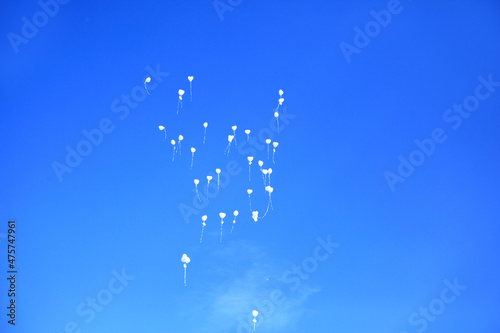 Białe balony w kształcie serc szybujące na tle niebieskiego nieba, wesele, uczucia i emocie, zasoby graficzne.