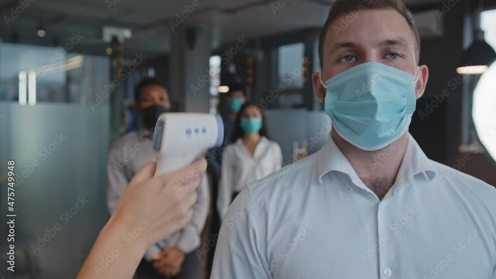 Masked Workers Multiracial employees measure temperature with electronic contactless ...