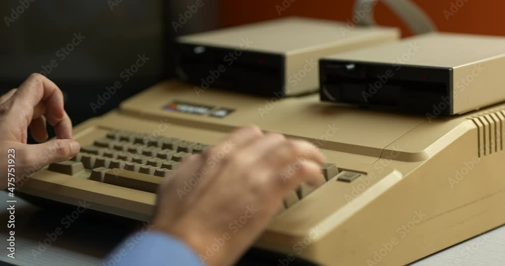 Man in blue shirt typing on old computer
