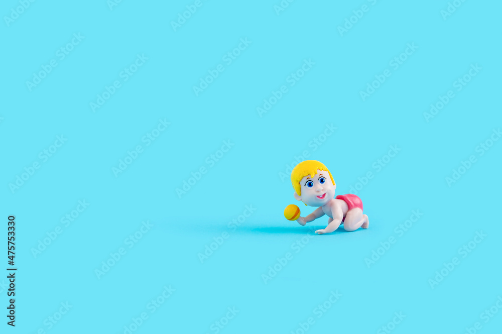 Baby doll with rattle on pastel blue background. Baby doll with rattle on pastel blue background.