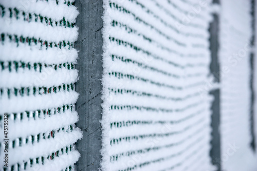 Detail on the structure of a fence covered with snow and icicles. The fence has metal posts.