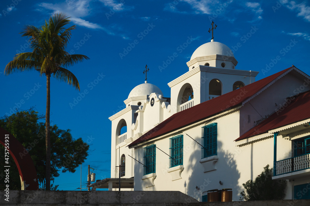 Sunlit church of Flores with palm tree, Peten, Guatemala