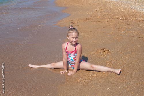 A little girl sits on a sandy seashore in a transverse twine. Summer vacation at the sea photo