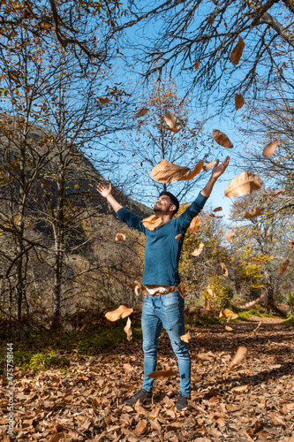 close up. young man plays with yellow leaves falling down. vertical composition © magui RF