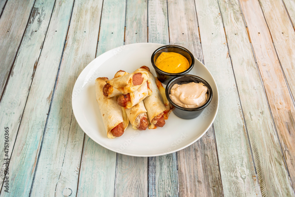 sausages wrapped in corn tortilla with cheese and dipping sauces sausages wrapped in corn tortilla with cheese and dipping sauces
