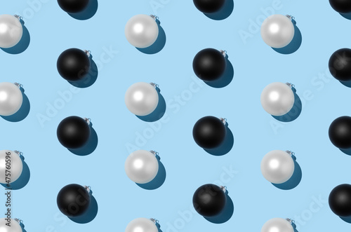 White and black Christmas balls pattern on a pastel blue background.
