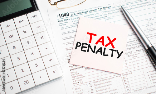 Tax penalty with pen, calculator, glass and sticker. Tax report sign photo