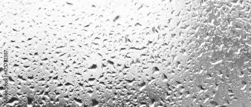 Water drops behind glass. Background from raindrops on the window. Black-and-white backdrop made of drips of water. Creative pattern