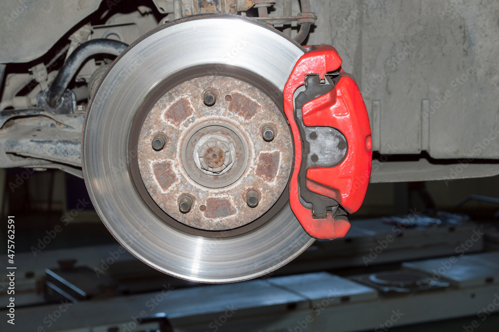 Red brake caliper mounted on the car's brake disc