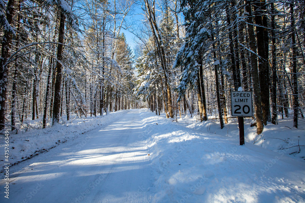 Speed limit sign next to a road winding through the trees in Council Grounds State Park, Merrill, Wisconsin after a snow storm