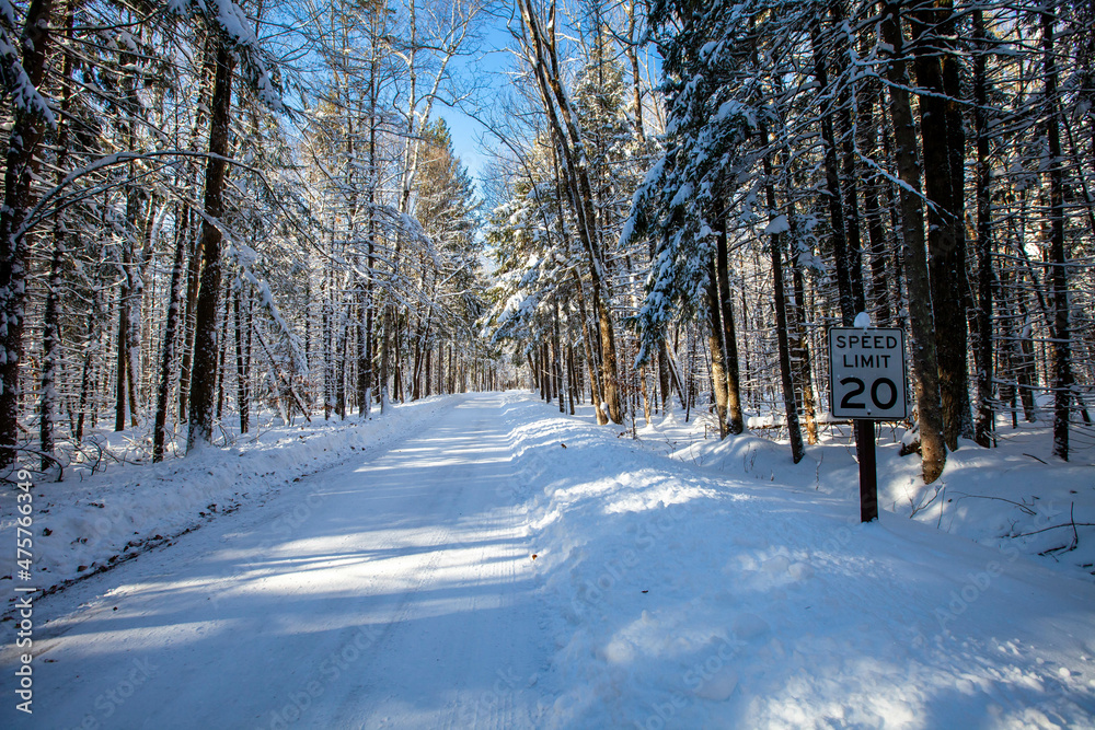 Speed limit sign next to a road winding through the trees in Council Grounds State Park, Merrill, Wisconsin after a snow storm Speed limit sign next to a road winding through the trees in Council Grounds State Park, Merrill, Wisconsin after a snow storm