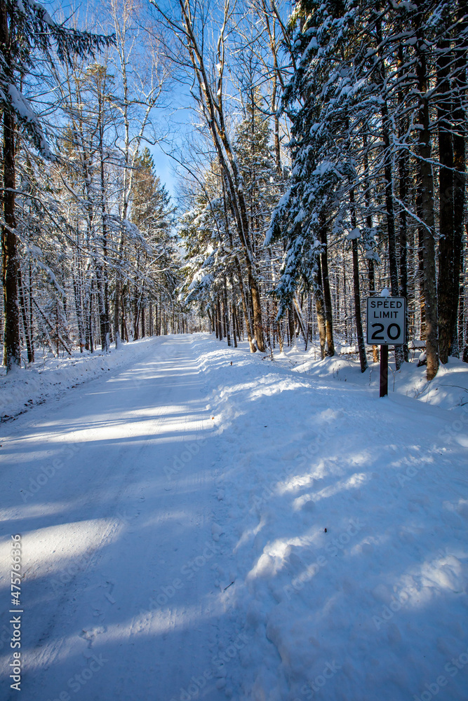 Speed limit sign next to a road winding through the trees in Council Grounds State Park, Merrill, Wisconsin after a snow storm