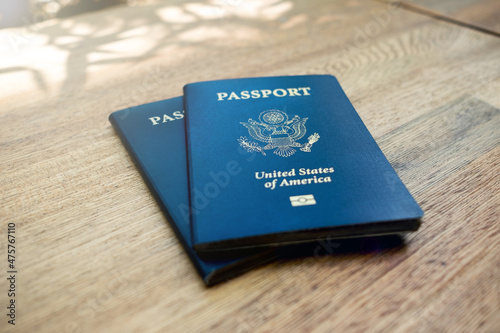 Two blue American passports laying on a wooden desk