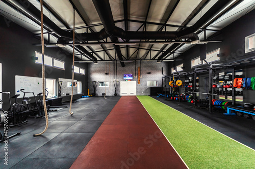 Interior of an urban gym with equipment. Sports center for a cross fit  aerobic  spinning class  functional training. In the middle of the sports center are artificial grass and a running track