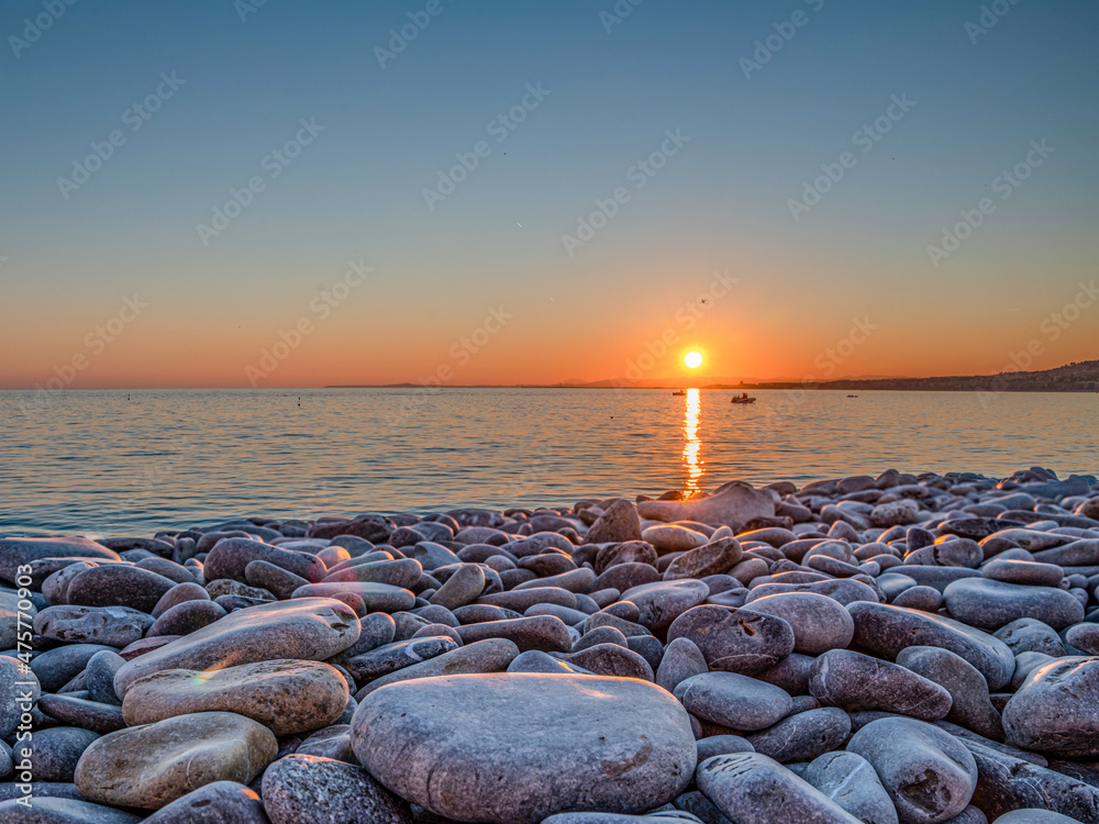 Coucher de soleil sur la baie des anges à Nice sur la Côte d'Azur avec une  plage de galets au premier plan Photos | Adobe Stock