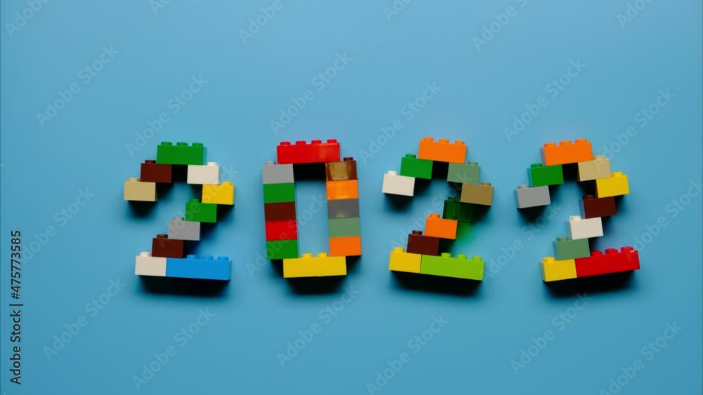 Stop motion of making symbol 2022 from colorful constructor blocks on blue background. Stop motion of making symbol 2022 from colorful constructor blocks on blue background.