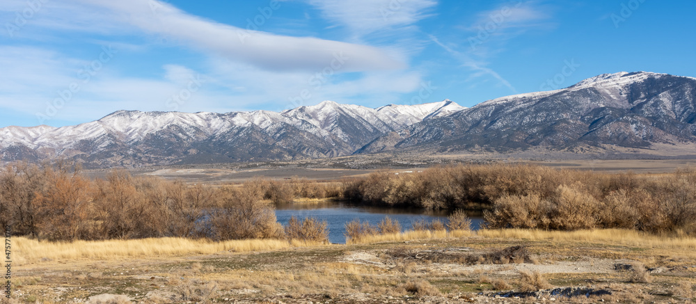 A lake in a prairie landscape with a distant snow covered mountain range