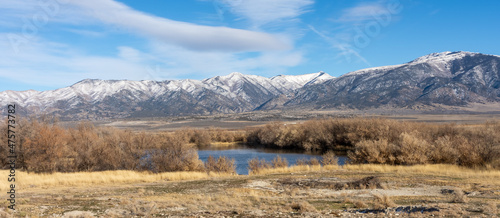Fotografie A lake in a prairie landscape with a distant snow covered mountain range