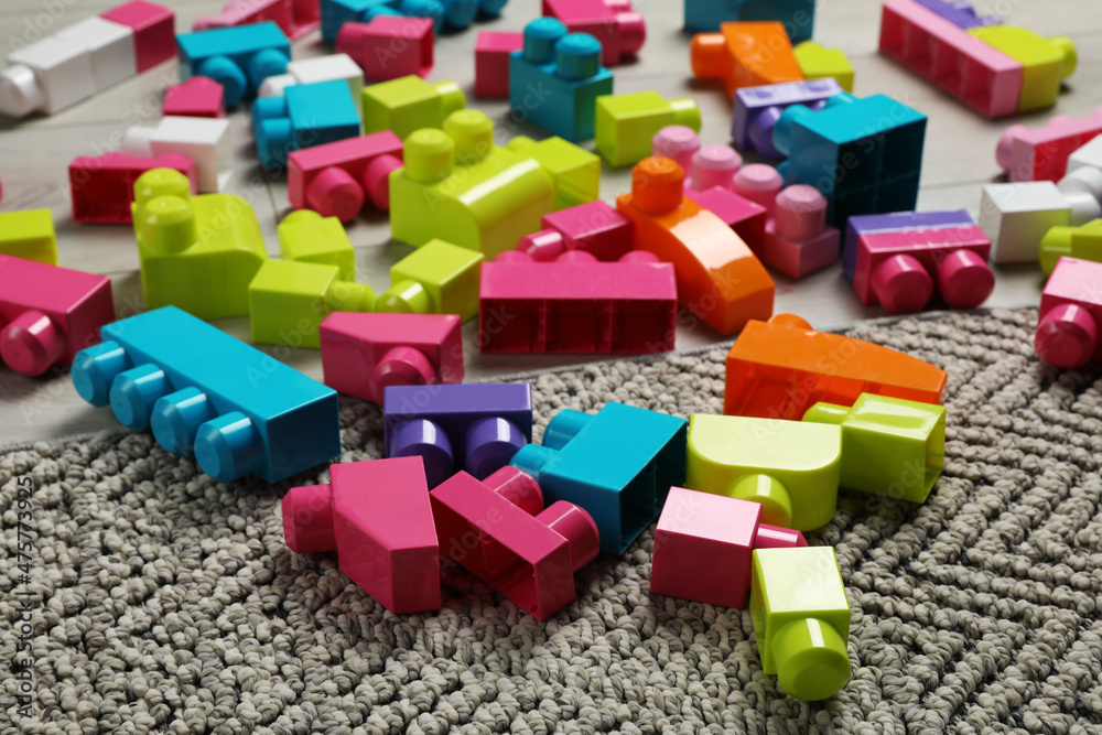 Fototapeta premium Colorful plastic building blocks on grey carpet
