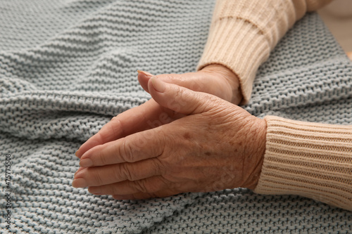 Elderly woman on grey knitted blanket, closeup