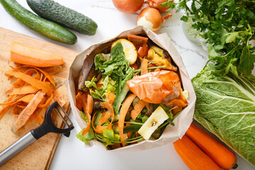 Sorted kitchen waste in paper eco bag on kitchen counter top. Compost-container. Sustainable life style. Vegetable and fruit peels, scraps from food preparation collected in trash-pack for recycling