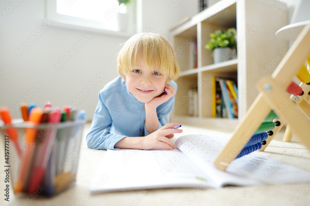 Elementary student boy doing homework at home. Child learning to count, solves arithmetic examples, doing exercises in workbook. Math tutorial. Preparing preschooler baby for school. Elementary student boy doing homework at home. Child learning to count, solves arithmetic examples, doing exercises in workbook. Math tutorial. Preparing preschooler baby for school.
