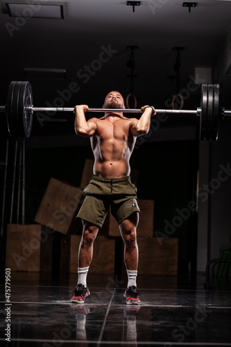 Muscular athlete lifting very heavy barbell