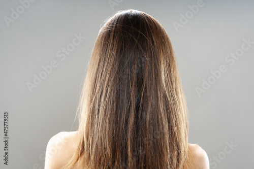 Brunette girl turned around studio portrait. Long hair shot form the back.