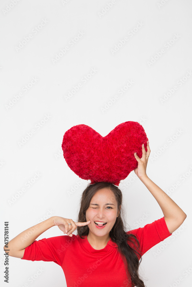 Beautiful Asian woman wearing small Santa hat and wearing red dress holding red heart shape pillow on white background Beautiful Asian woman wearing small Santa hat and wearing red dress holding red heart shape pillow on white background