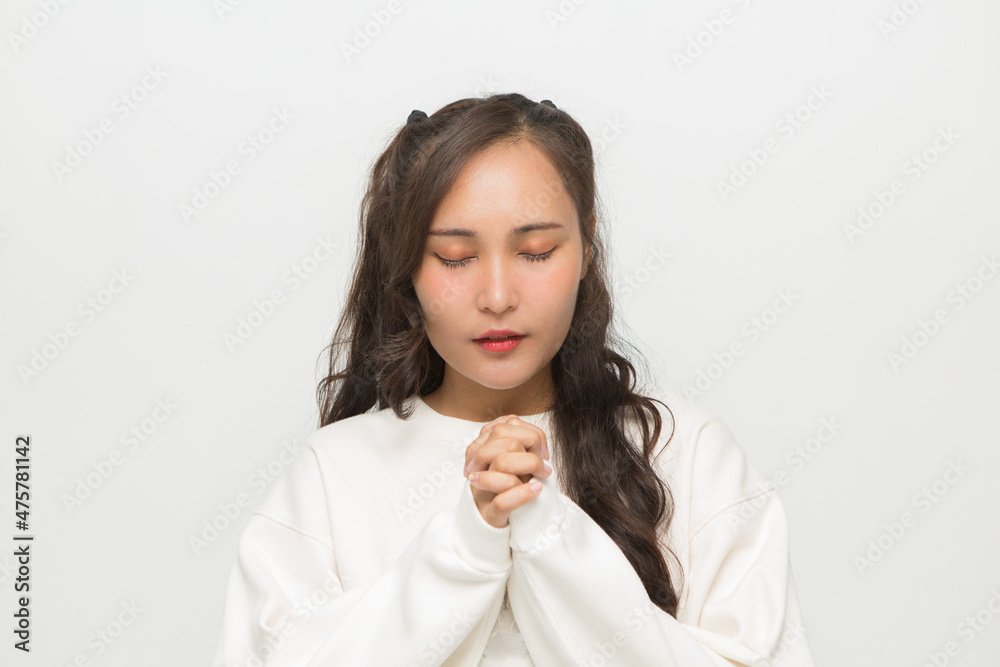 Beautiful Asian woman wearing white sweater praying on white background. Beautiful Asian woman wearing white sweater praying on white background.