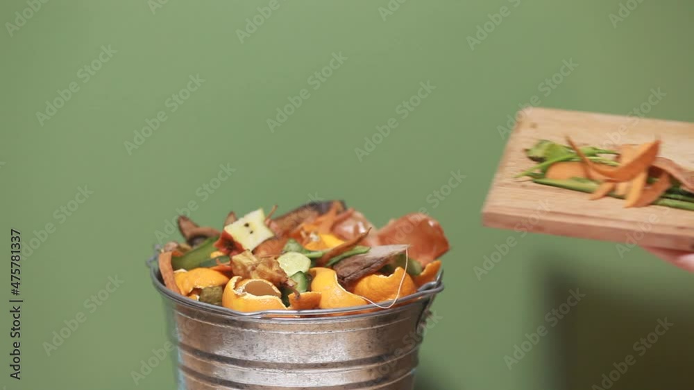 Woman throws vegetable peeling, scraps in compost bucket. Food waste