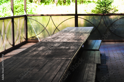 Covered seating area with long wooden table and benches.