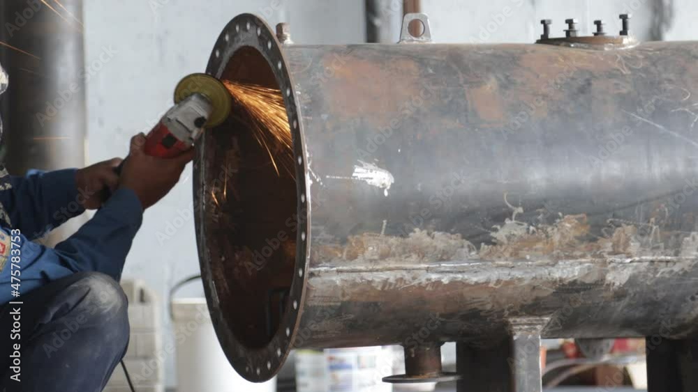 construction worker smoothing steel surface with hand grinder