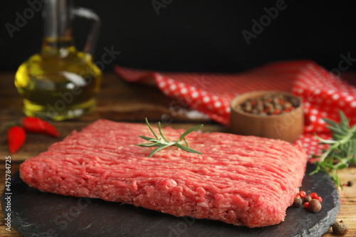 Raw fresh minced meat and other ingredients on wooden table, closeup
