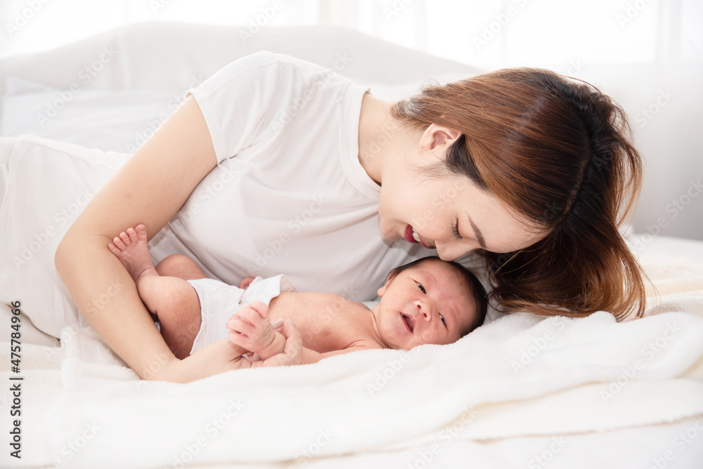 Asian loving mom carying of her newborn baby at home. Happy mum holding sleeping infant child on hands. Mother hugging her little one months old son.