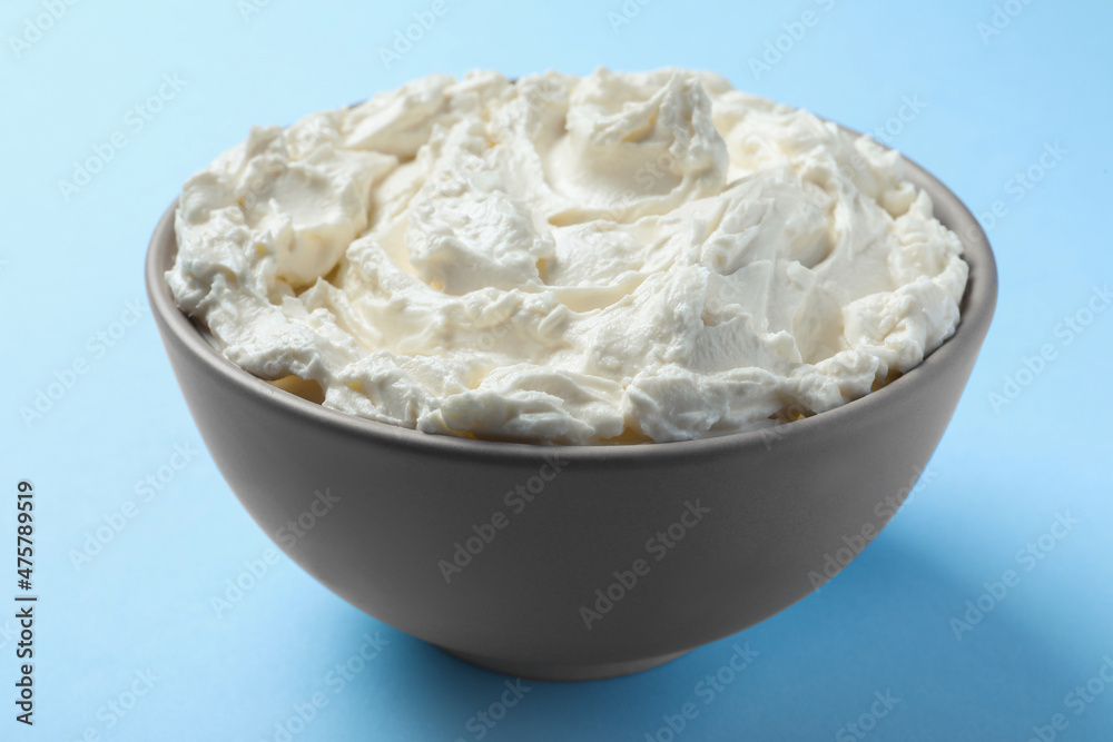 Bowl of tasty cream cheese on light blue background, closeup Bowl of tasty cream cheese on light blue background, closeup