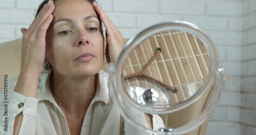 Reflected face skin looking in mirror. A female examine her face reflection on the small mirror on the table. Reflected face skin looking in mirror. A female examine her face reflection on the small mirror on the table.