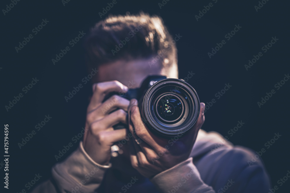 A man photographer with a camera takes a photo in the dark.