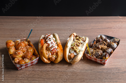 View of delicious hot dogs and tasty fried doughnuts on the wooden surfac photo