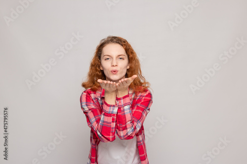 red-haired young girl in a plaid shirt on a white background with a place for text
